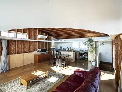 Industrial-style living room with wooden-paneled walls, leather sofa, and wooden coffee table.