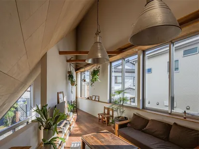 A modern industrial living room with wooden floors, glass windows, and metal pendant lights.