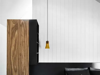 A modern minimalist bedroom with a wooden headboard and pendant light hanging from the ceiling.