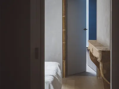 簡約臥室內，一張鋪著白色床罩的床，搭配紋理毯子與石材壁爐檯面。
