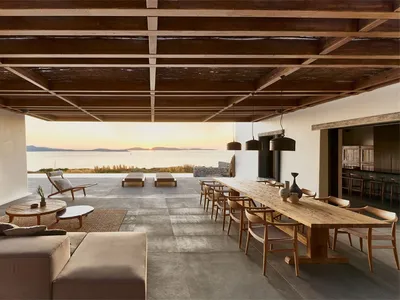 Contemporary residential living room featuring wooden furniture and concrete flooring with a view of the sunset.