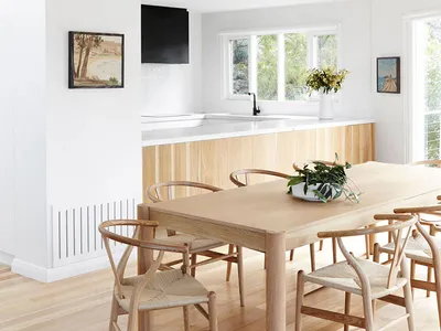 Modern kitchen with a wooden dining table and chairs, white countertop, and large windows.