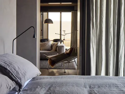 A minimalist bedroom featuring a grey bed, cotton-blend curtains, and a wooden ceiling.