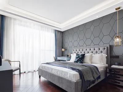 A modern bedroom featuring a grey upholstered bed with a geometric pattern on one wall.