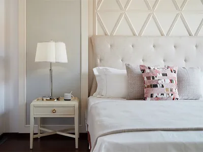 A cozy, modern bedroom featuring a white upholstered bed with a textured tufted headboard, set against a soft, patterned tile
