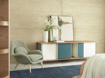 A minimalist bedroom featuring a wooden storage unit, a fabric armchair, and a navy blue rug.