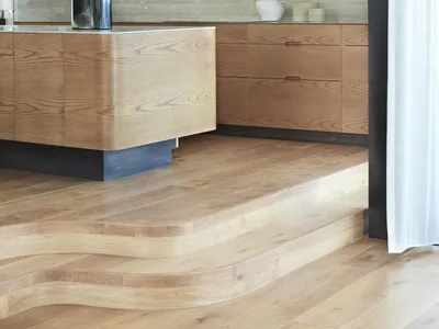 A modern kitchen interior featuring wooden cabinets and a natural wooden floor.