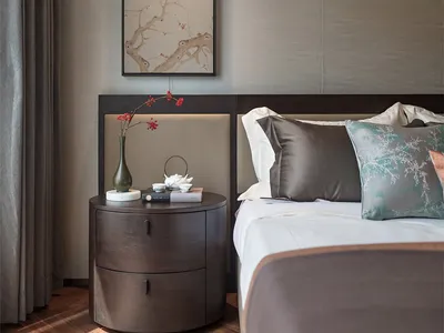 A modern bedroom featuring a bed with brown bedding, a wooden nightstand, and a floral painting above it.