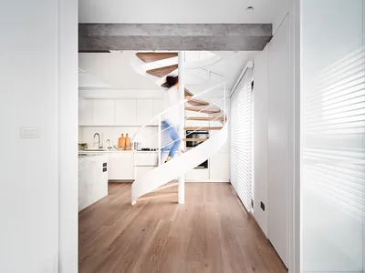 A modern kitchen with wooden flooring, metal railings, and marble countertops, featuring a spiral staircase.