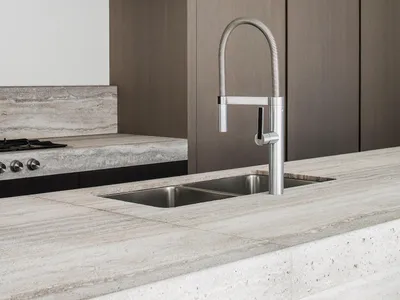 A modern kitchen with a stone countertop and a waterfall edge sink.