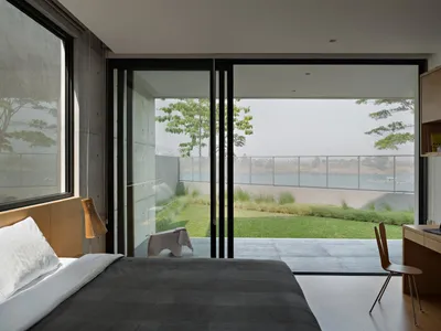 A minimalist bedroom featuring a bed with a wooden headboard and a glass coffee table.