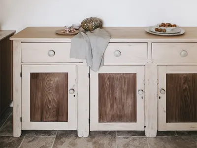 A minimalist kitchen with white cabinets and wooden accents, featuring decorative ceramics on shelves.