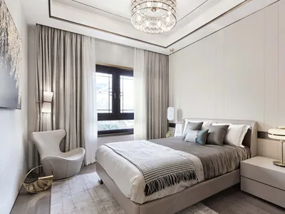 A modern bedroom featuring gray and taupe colors with a bed, nightstands, and a contemporary armchair.
