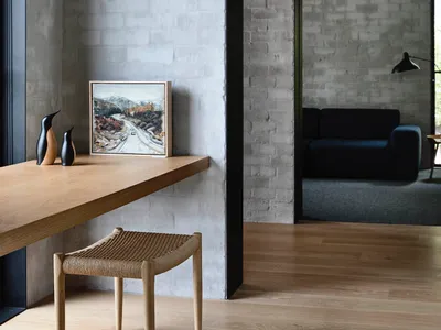 A modern home office with a wooden desk, concrete walls, and brick accents.