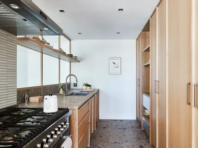 Modern kitchen featuring minimalist design with wood cabinetry and marble countertops.