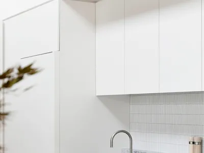 Modern, minimalist kitchen with marble countertops and white cabinets.
