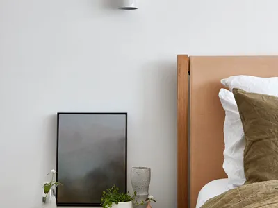 A minimalist bedroom featuring a wood headboard and neutral color scheme.