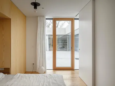 A minimalist bedroom with wooden furniture and a glass door.