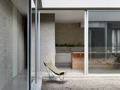 Modern minimalist residential kitchen with concrete walls and flooring, featuring a small island with a wooden countertop.