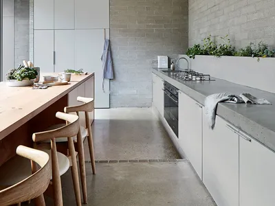 Modern minimalist residential kitchen with concrete countertops and white cabinets.