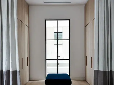 Minimalist bedroom showcasing a contemporary bench and bench-induction concrete gray flooring with neutral-colored curtains a