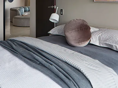 A minimalist bedroom with grey and taupe tones, featuring a bed, pillows, and a painting.