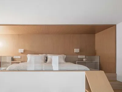 A minimalist bedroom with wooden elements, including a bed, nightstands, and a ceiling.
