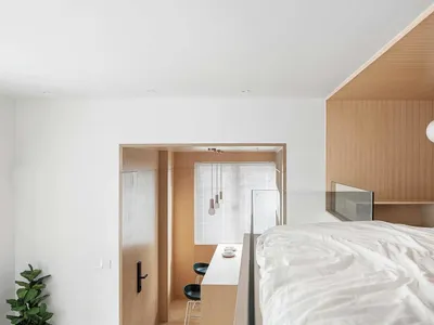 A minimalist bedroom with wooden walls and white bedding.