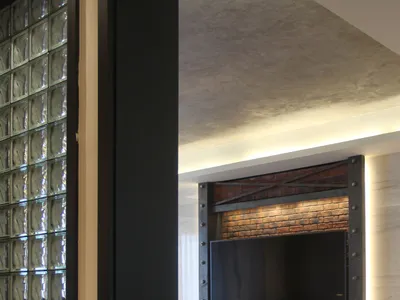 A modern industrial living room with a concrete floor, exposed brick walls, and steel accents.