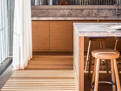 Modern kitchen featuring wooden cabinets and marble countertops with a bar table and stools.