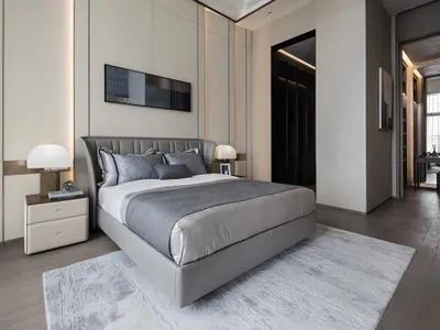 Modern minimalist bedroom featuring a grey leather bed with matching quilt and pillows, wooden flooring, and a modern rug. Wa