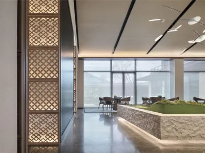 A modern restaurant lobby with marble flooring, stone walls, and glass walls.