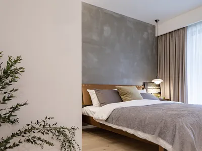 A stylish minimalist bedroom featuring a concrete accent wall and a wooden bedframe.