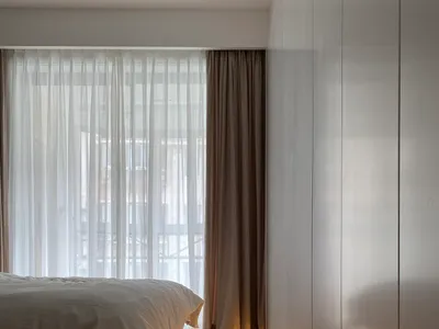 A minimalist bedroom featuring hardwood flooring and a fabric bed.