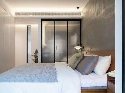 A minimalist bedroom featuring a bed with wooden frame, metal details, and a glass door wardrobe.