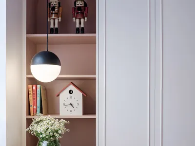 Modern, minimalist home office with shelves, books, and a birdhouse clock.