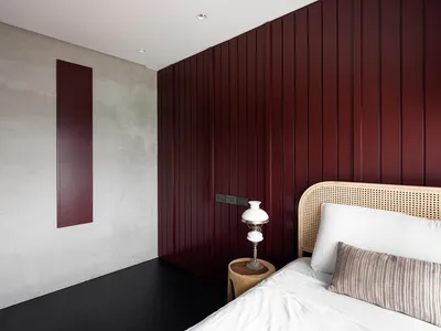 Modern bedroom featuring burgundy accent wall and rattan bedding