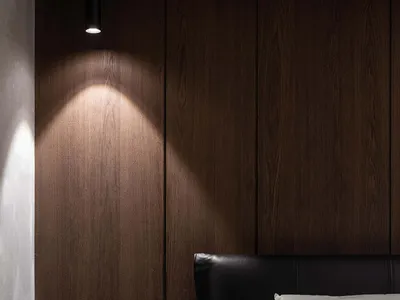 A minimalist bedroom with a wood-paneled wall and white bedding.