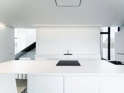 Modern minimalist kitchen with white laminates and a black countertop.