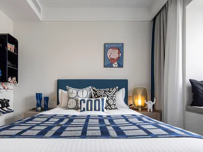 Modern bedroom featuring a white bed with blue and white checkered blanket and decorative pillows placed against a light gray