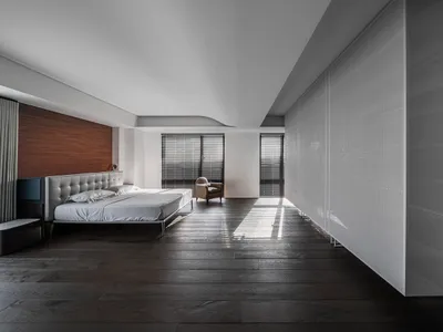 Modern minimalist bedroom featuring a wood-finished bed and glass panels.