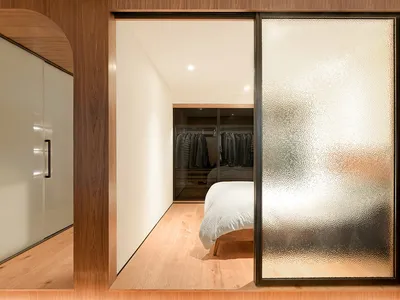 A minimalist bedroom with a bed, closet, and wooden floors.