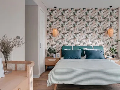 A modern Scandinavian bedroom featuring a bed with a teal headboard and striped bedding, against a feather-patterned wallpape
