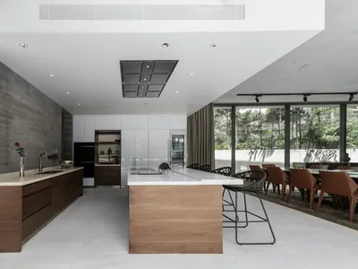 Modern kitchen with wooden countertops, concrete walls, and a large dining area.