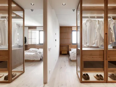 A modern minimalist bedroom featuring a large wooden closet with clothes hanging.