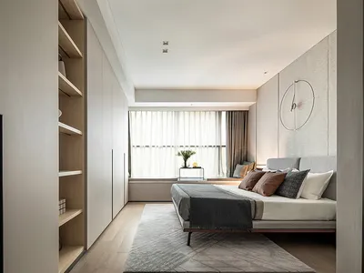A modern minimalist bedroom featuring neutral tones and a tidy, organized space.