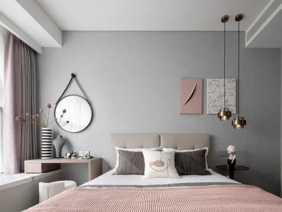 A minimalist bedroom with a grey accent wall, featuring a bed with geometrically patterned pillows, a round mirror, and abstr