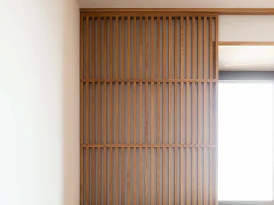 A modern, minimalist bedroom with wooden storage units, white bedding, and a window.