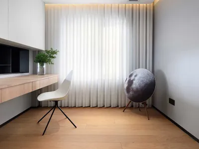 Modern minimalist home office featuring a sleek desk, white chair, white curtains, and a hanging air diffuser.