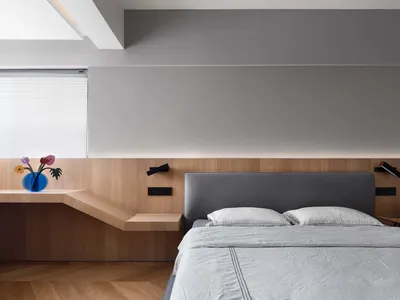 Minimalist bedroom with wooden furniture, grey headboard, and grey bedding
